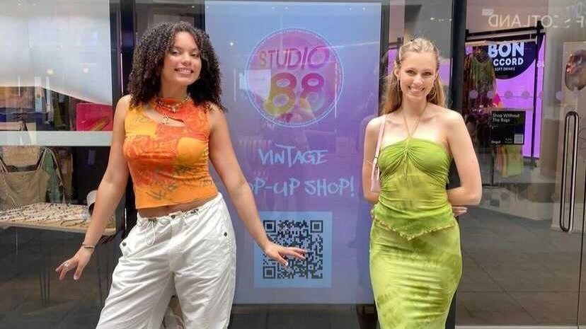 Two depopers outside Studio 88 pop up posing in front of screen with their branding on it