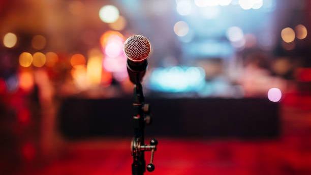 microphone on stage in front of evening lights and audience